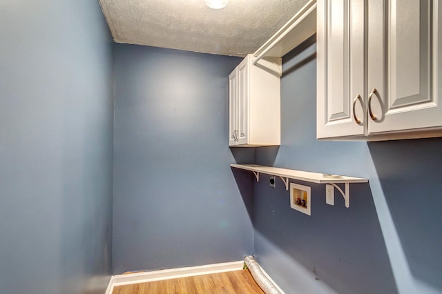 washroom with cabinets, light hardwood / wood-style flooring, a textured ceiling, and hookup for a washing machine