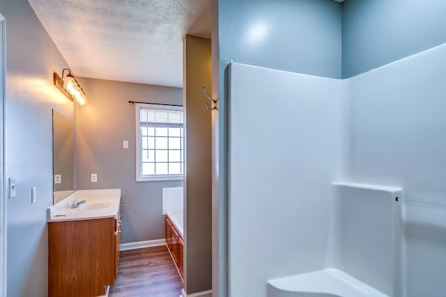 bathroom featuring vanity, a textured ceiling, hardwood / wood-style flooring, and a bathing tub