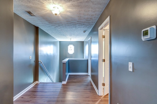 corridor featuring a textured ceiling and hardwood / wood-style flooring