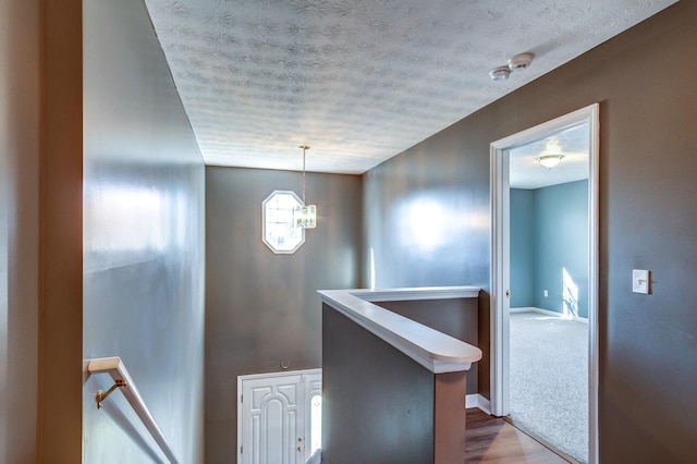 corridor featuring hardwood / wood-style floors, a chandelier, and a textured ceiling