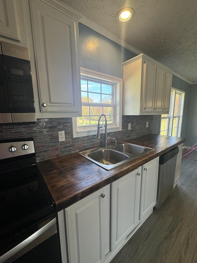 kitchen with wooden counters, sink, appliances with stainless steel finishes, and a textured ceiling