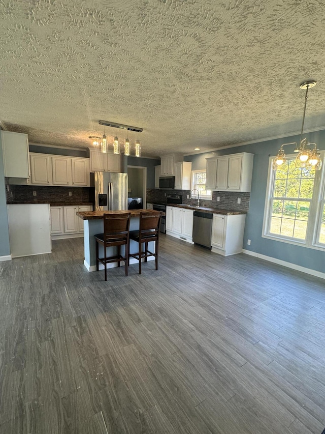 kitchen with white cabinets, stainless steel appliances, hanging light fixtures, and a kitchen island