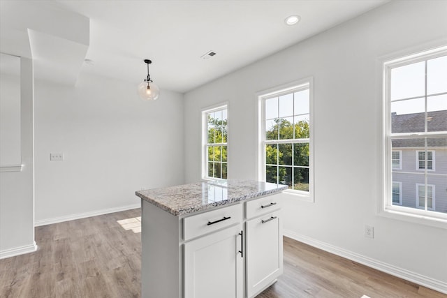 kitchen featuring white cabinets, a center island, light hardwood / wood-style flooring, and hanging light fixtures