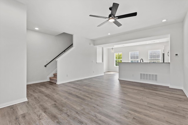 unfurnished living room featuring sink, light wood-type flooring, and ceiling fan