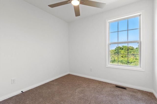 carpeted spare room featuring a wealth of natural light and ceiling fan