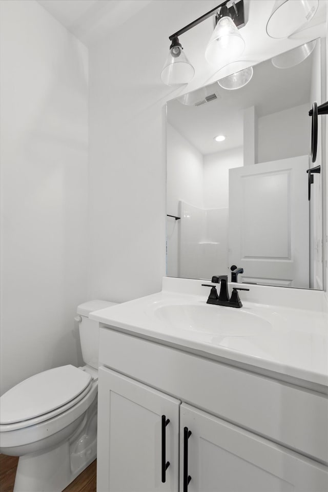 bathroom featuring toilet, hardwood / wood-style floors, and vanity