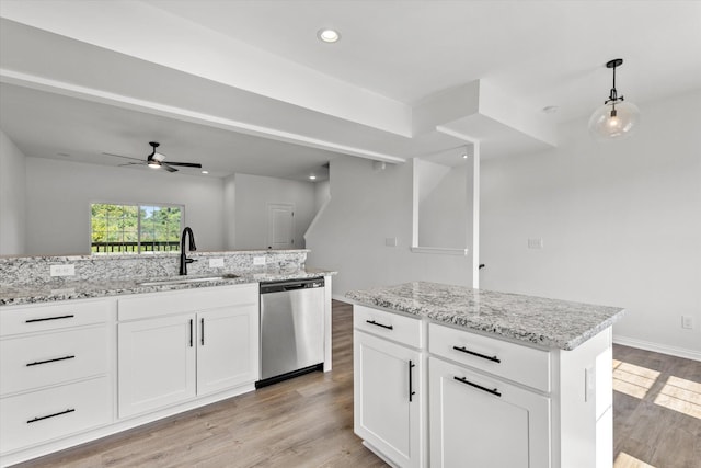 kitchen featuring white cabinets, stainless steel dishwasher, sink, and a kitchen island