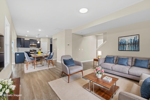 living area featuring baseboards, recessed lighting, and light wood finished floors