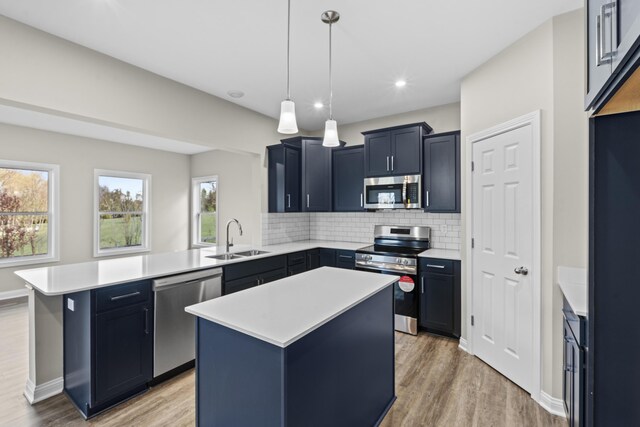 kitchen featuring sink, a kitchen island, light hardwood / wood-style floors, and appliances with stainless steel finishes