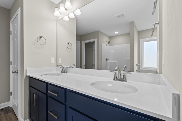 bathroom featuring double vanity, visible vents, a shower, and a sink