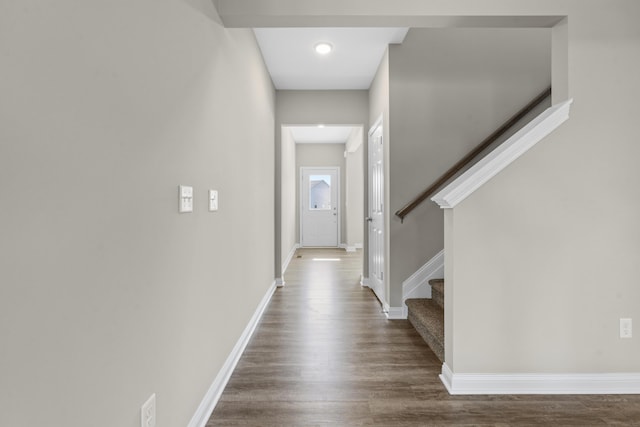 hallway featuring baseboards, stairway, and dark wood-type flooring