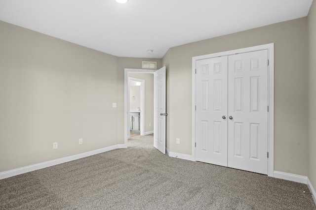 unfurnished bedroom with a closet, carpet, and baseboards