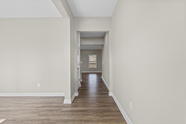 corridor with dark wood-type flooring and baseboards