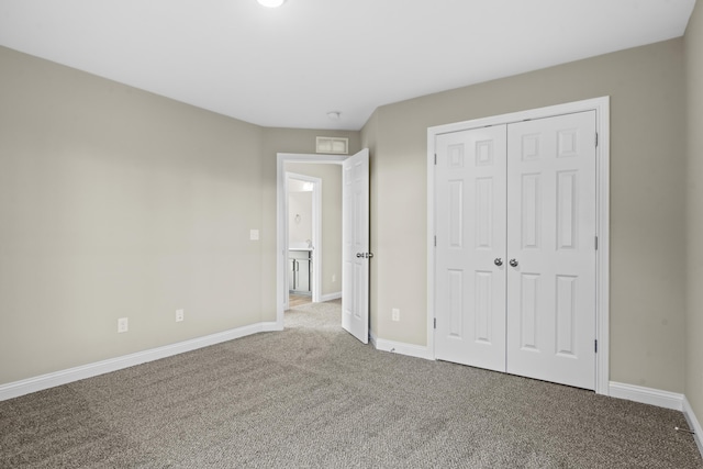 unfurnished bedroom with baseboards, carpet floors, and a closet