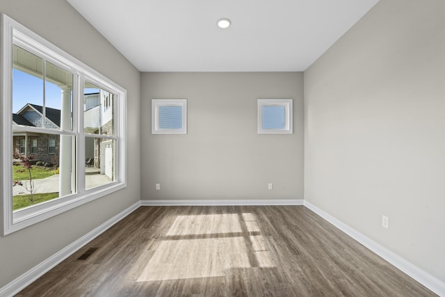 empty room featuring wood finished floors, visible vents, and baseboards