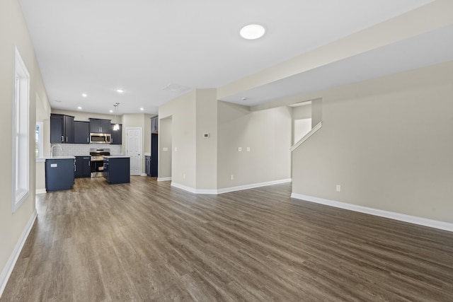 unfurnished living room featuring dark wood-style floors, recessed lighting, and baseboards