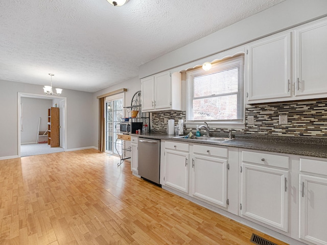 kitchen with stainless steel appliances, a chandelier, a textured ceiling, light hardwood / wood-style floors, and white cabinets