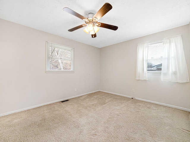 spare room with carpet, a wealth of natural light, and ceiling fan