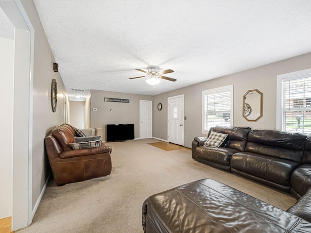 carpeted living room with ceiling fan and a textured ceiling