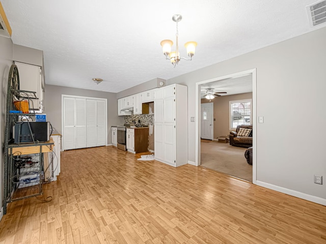 kitchen with stainless steel appliances, an inviting chandelier, tasteful backsplash, white cabinets, and light wood-type flooring