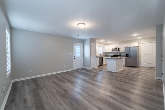 kitchen with white cabinetry, stainless steel appliances, wood-type flooring, and a kitchen island