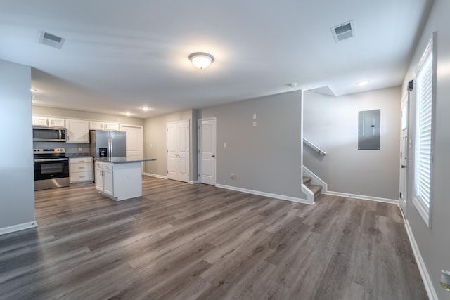 kitchen featuring a kitchen island, dark wood-type flooring, white cabinets, electric panel, and appliances with stainless steel finishes