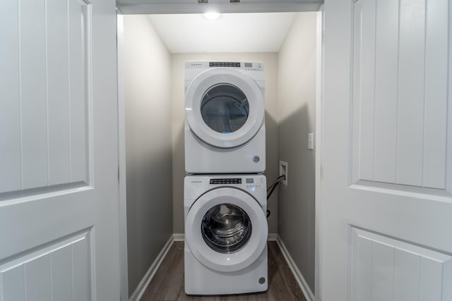 laundry room featuring stacked washer and dryer and dark hardwood / wood-style floors