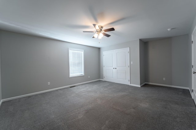 spare room with ceiling fan and dark colored carpet