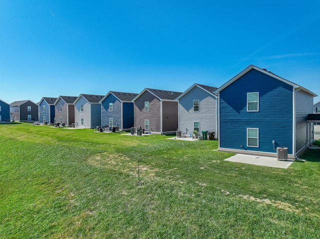 back of property with cooling unit, a patio area, and a lawn