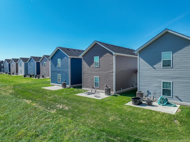 rear view of property featuring central air condition unit, a patio area, and a lawn