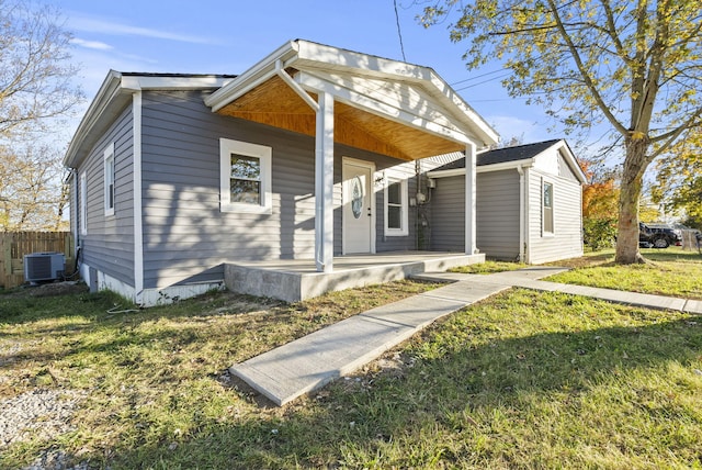 bungalow-style house featuring a porch, a front lawn, and central AC