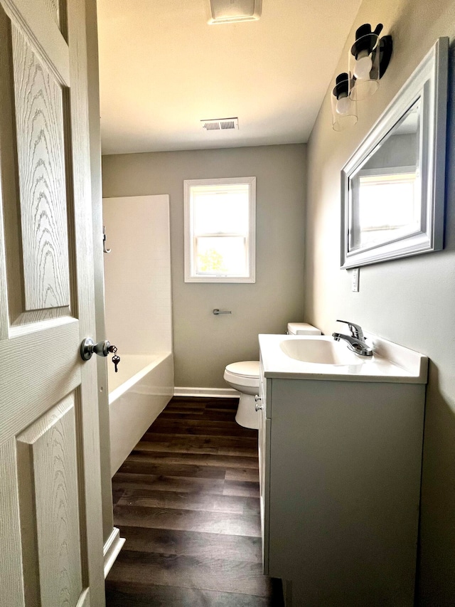 bathroom featuring vanity, a tub to relax in, toilet, and hardwood / wood-style floors