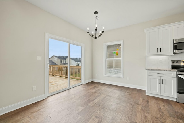 unfurnished dining area with a notable chandelier, baseboards, and wood finished floors