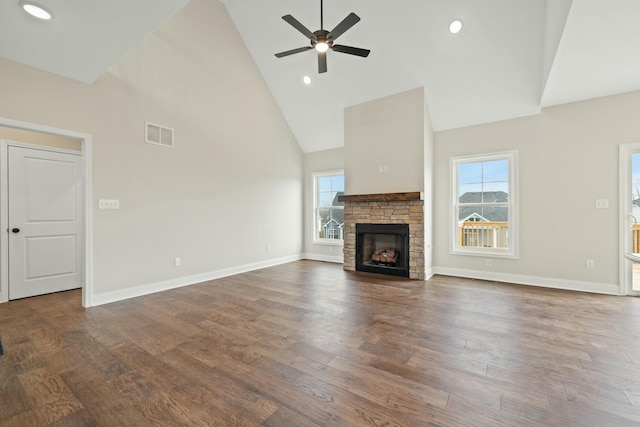 unfurnished living room featuring visible vents, ceiling fan, a stone fireplace, wood finished floors, and high vaulted ceiling