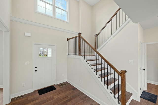 entryway with a towering ceiling, dark wood-style floors, baseboards, and a wealth of natural light