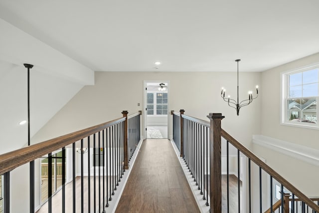 hallway with an inviting chandelier, recessed lighting, wood finished floors, and an upstairs landing