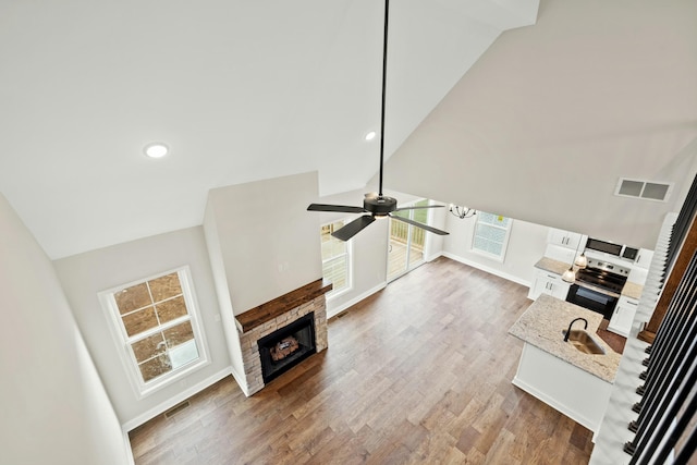 unfurnished living room with lofted ceiling, a fireplace, a sink, and visible vents