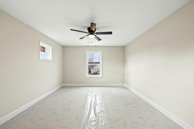 unfurnished room featuring light colored carpet, ceiling fan, and baseboards