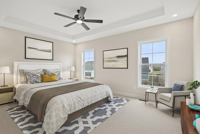 carpeted bedroom featuring ceiling fan and a tray ceiling