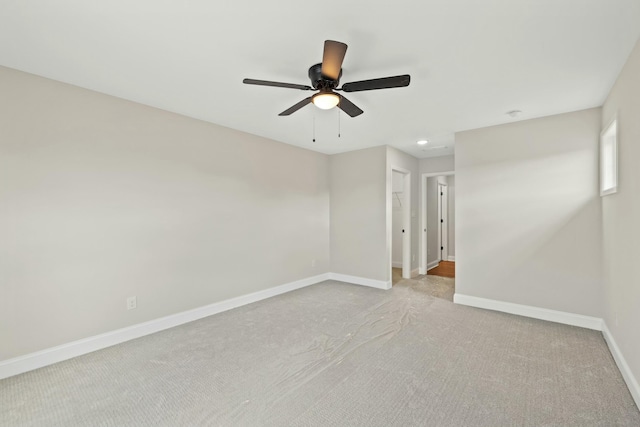 spare room featuring baseboards, a ceiling fan, and light colored carpet