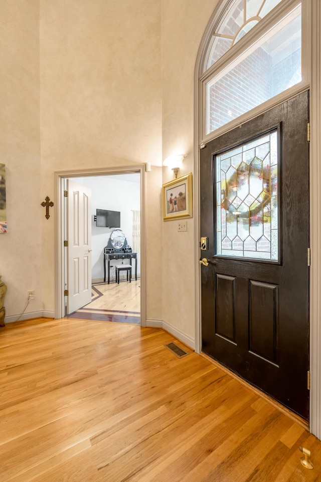 foyer with light hardwood / wood-style flooring and a high ceiling