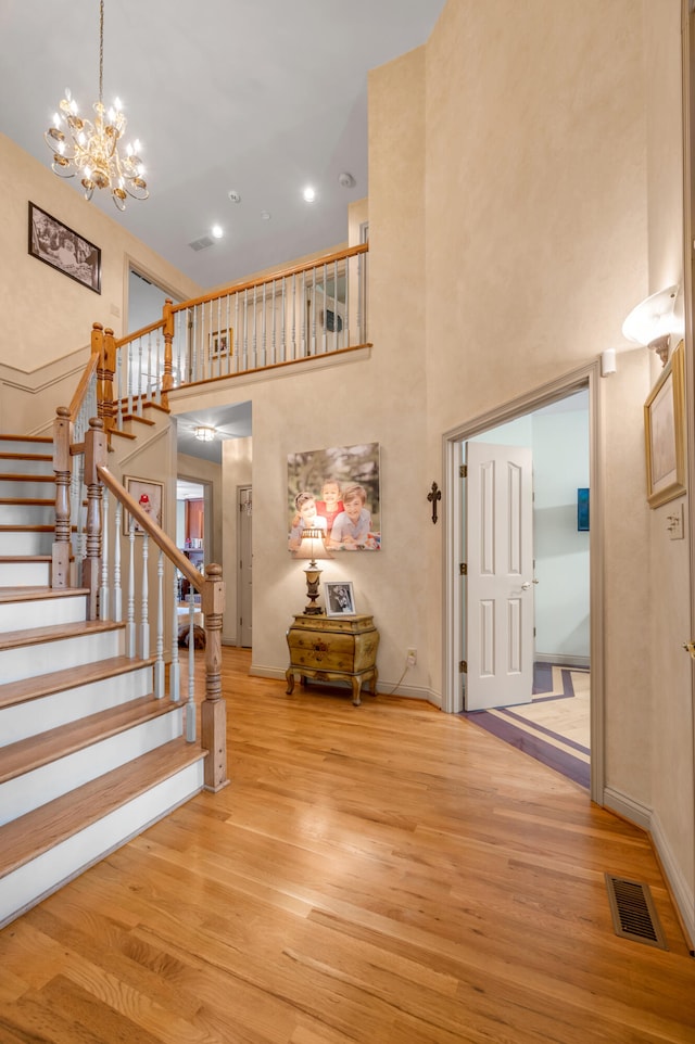 entryway with an inviting chandelier, a high ceiling, and light wood-type flooring