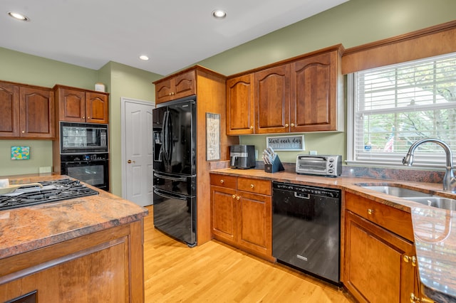 kitchen with light hardwood / wood-style flooring, black appliances, and sink