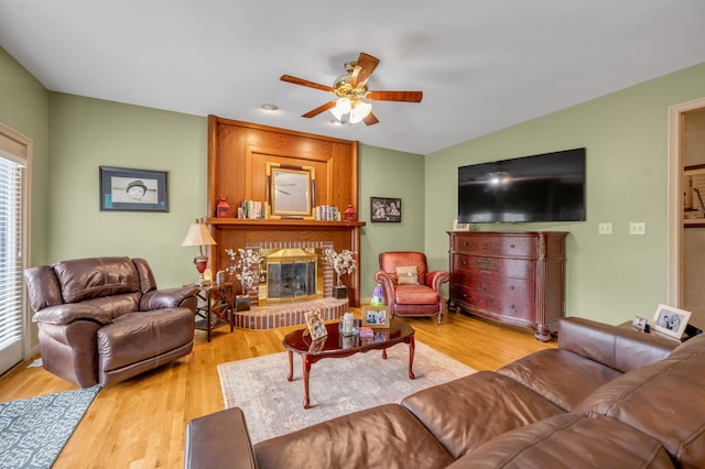 living room with hardwood / wood-style floors, a brick fireplace, and ceiling fan