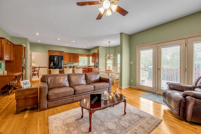 living room featuring sink, light hardwood / wood-style flooring, and ceiling fan with notable chandelier