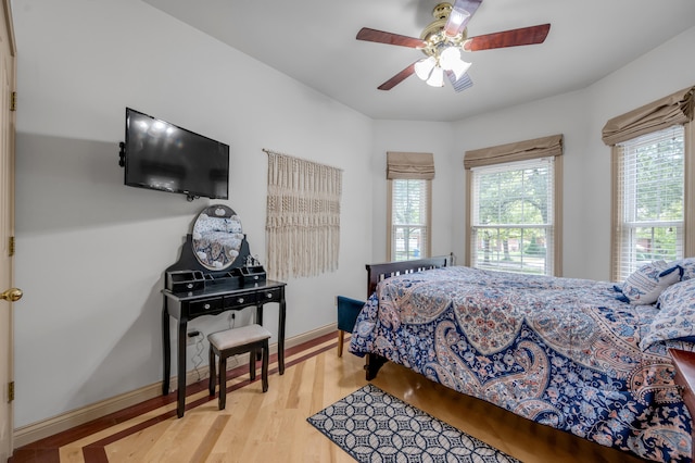 bedroom with multiple windows, hardwood / wood-style flooring, and ceiling fan