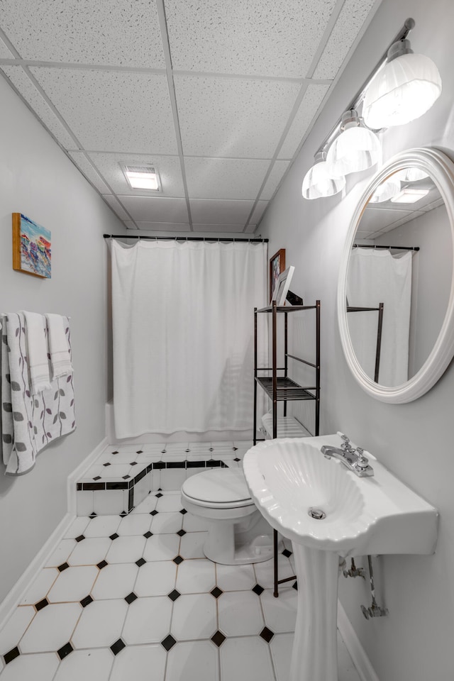 bathroom with a drop ceiling, a shower with curtain, and toilet