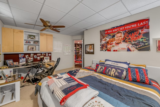 carpeted bedroom with ceiling fan and a drop ceiling