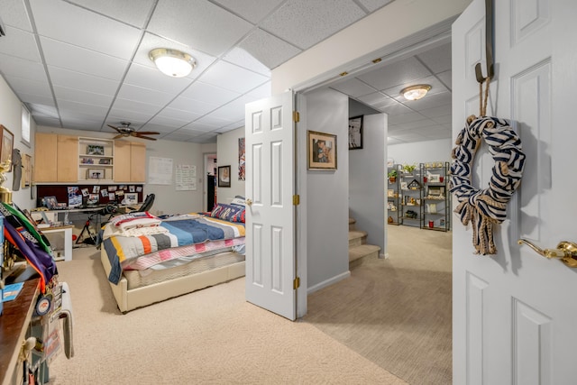 bedroom with a drop ceiling and light carpet