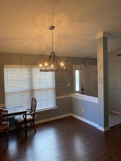 unfurnished dining area featuring a notable chandelier and dark hardwood / wood-style flooring